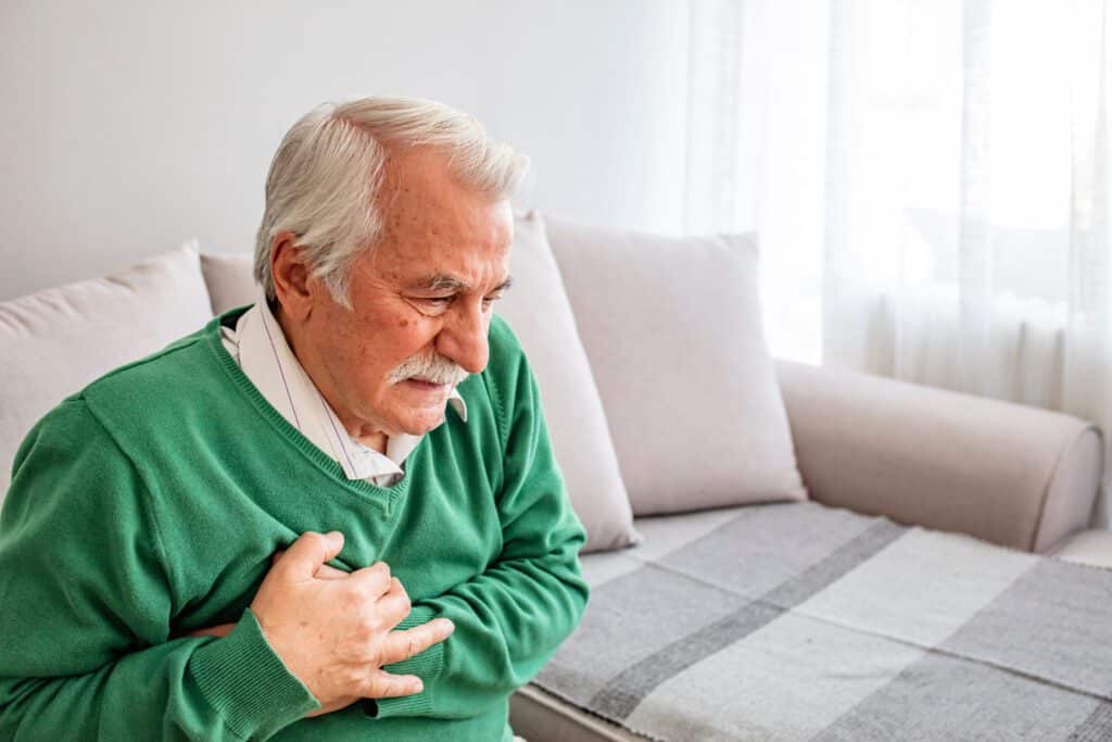 Senior man suffering from bad pain in his chest heart attack at home - senior heart disease. This could be a heart attack. Senior man suffering from heart attack at home