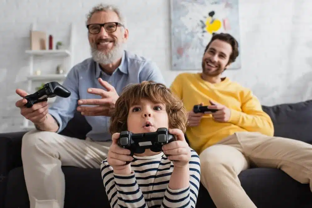 criança jogando videogame com seu pai e seu avô na sala