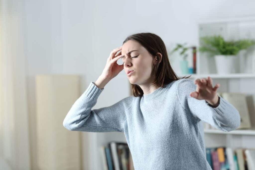 mulher com tontura em uma sala — um dos sintomas da taquicardia 