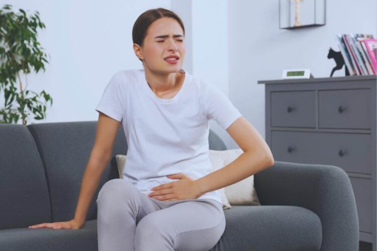mulher está sentada em um sofá com dores de infecção de urina