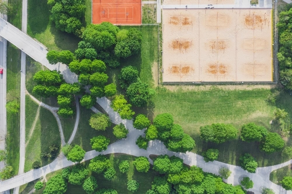 visão aérea de onde se joga beach tennis com árvores e uma quadra