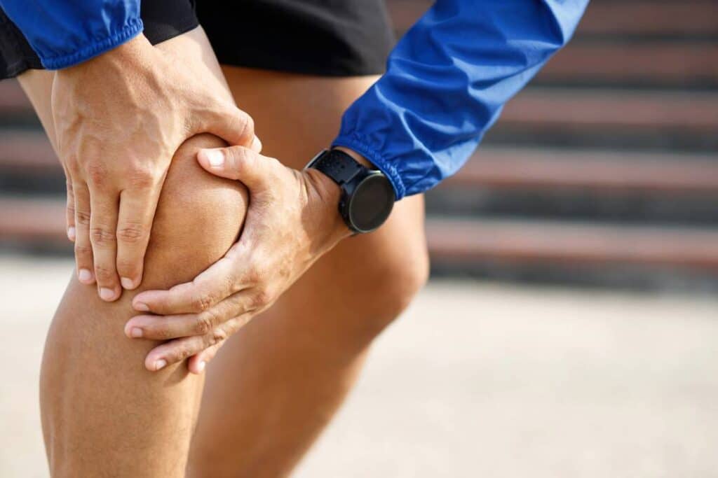 atleta corredor com as mãos sobre o joelho sinalizando dor