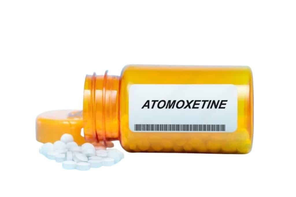 medicamento atomoxetina com a tampa aberta e com o remédio espalhado sobre uma superficie