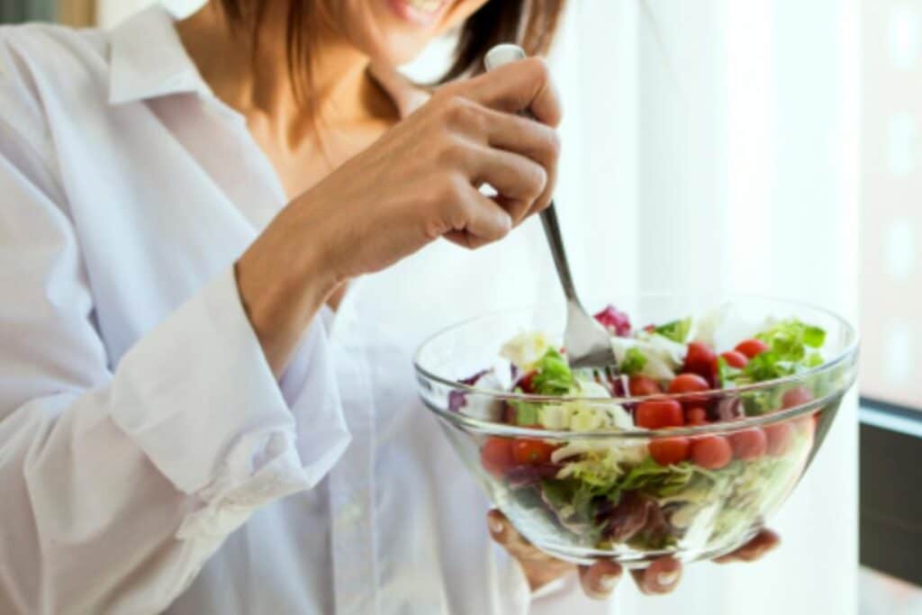 mulher segurando uma vasilha de salada com tomate e alface