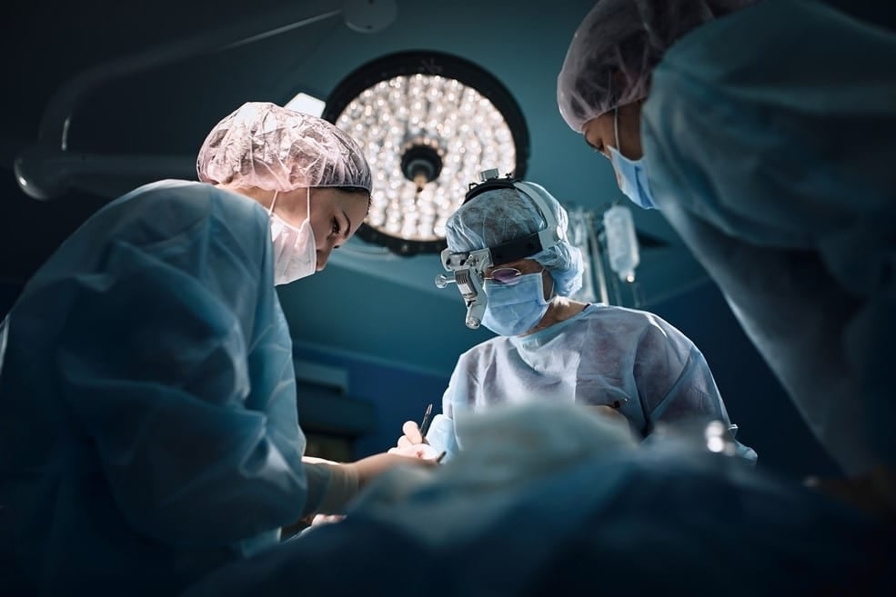 Três médicos realizando uma cirurgia após um Infarto Agudo do Miocárdio
