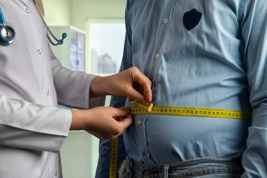 um médico está com uma fita métrica — medindo a barriga de um homem