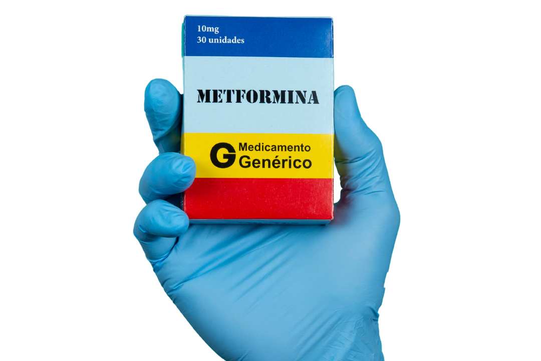 uma mão com uma luva azul está segurando uma caixa do medicamento metformina