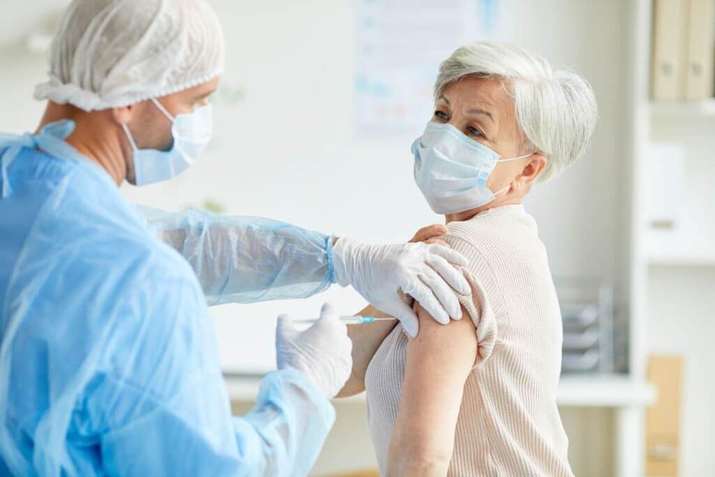 enfermeiro aplicando a vacina da gripe em uma senhora