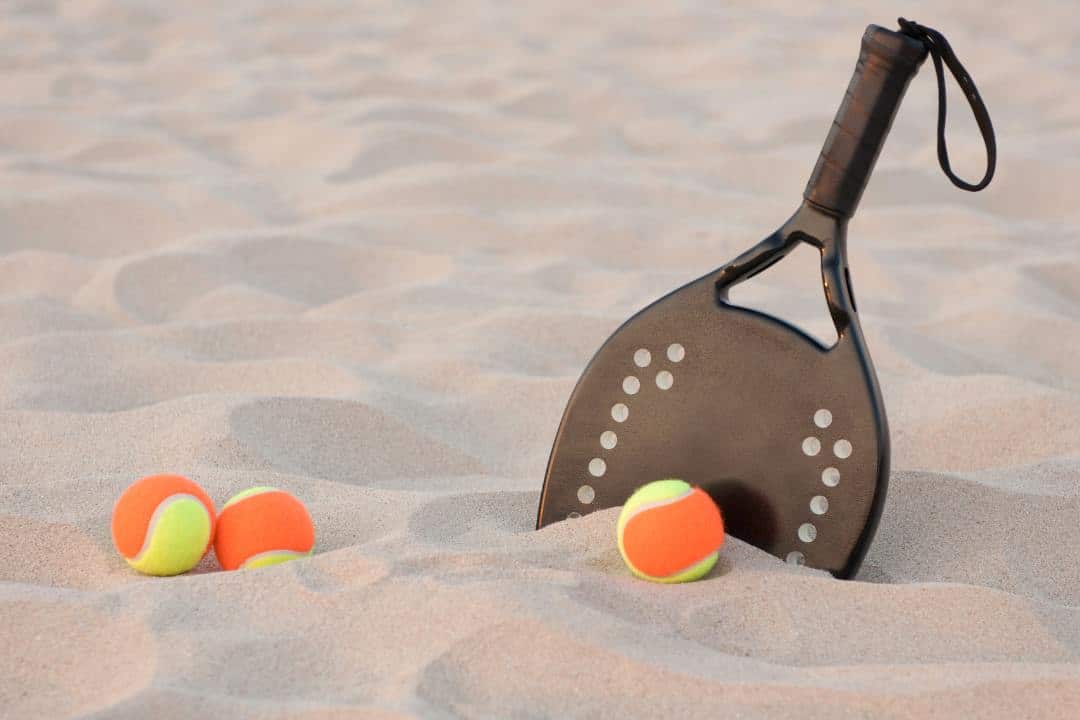 raquete de beach tênis e bolas de beach tennis na areia da praia