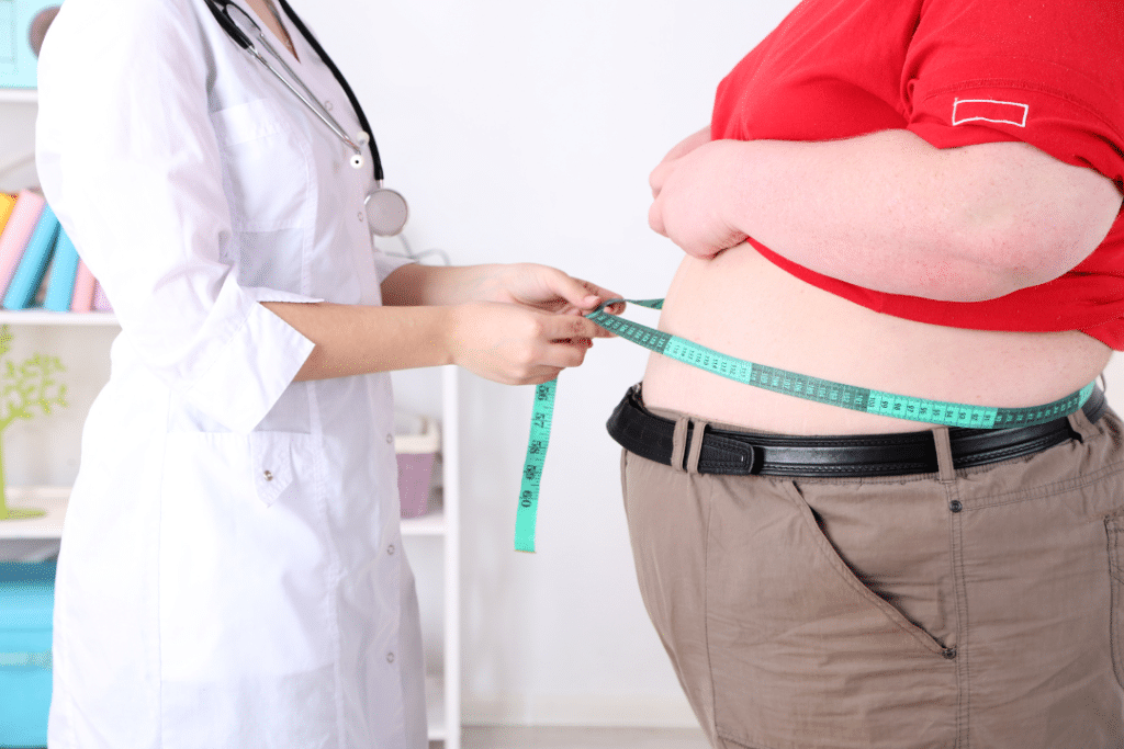 médica com uma fita métrica tirando medidas de um homem com obesidade